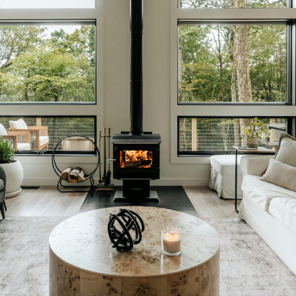 Skantherm Kamin - Herobild _ Wohnzimmer mit großen Fenstern, Kamin in der Mitte